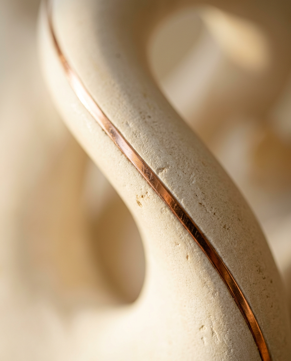 Close-up of a sculpted ivory curve with a fine copper inlay catching soft raking light.